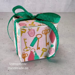 handdekorierte Fensterschachtel mit Glückwunsch-Anhänger, Geschenkbox mit Schlüsselmotiv und grünem Band, Nahaufnahme Fenster der Schachtel mit Füllung, runder Anhänger mit Schloss und Schlüssel, Schachtel geöffnet mit sichtbarem Inhalt, Glückwunsch-Tag an Geschenkbox, Geschenkverpackung für Einzug oder Prüfung